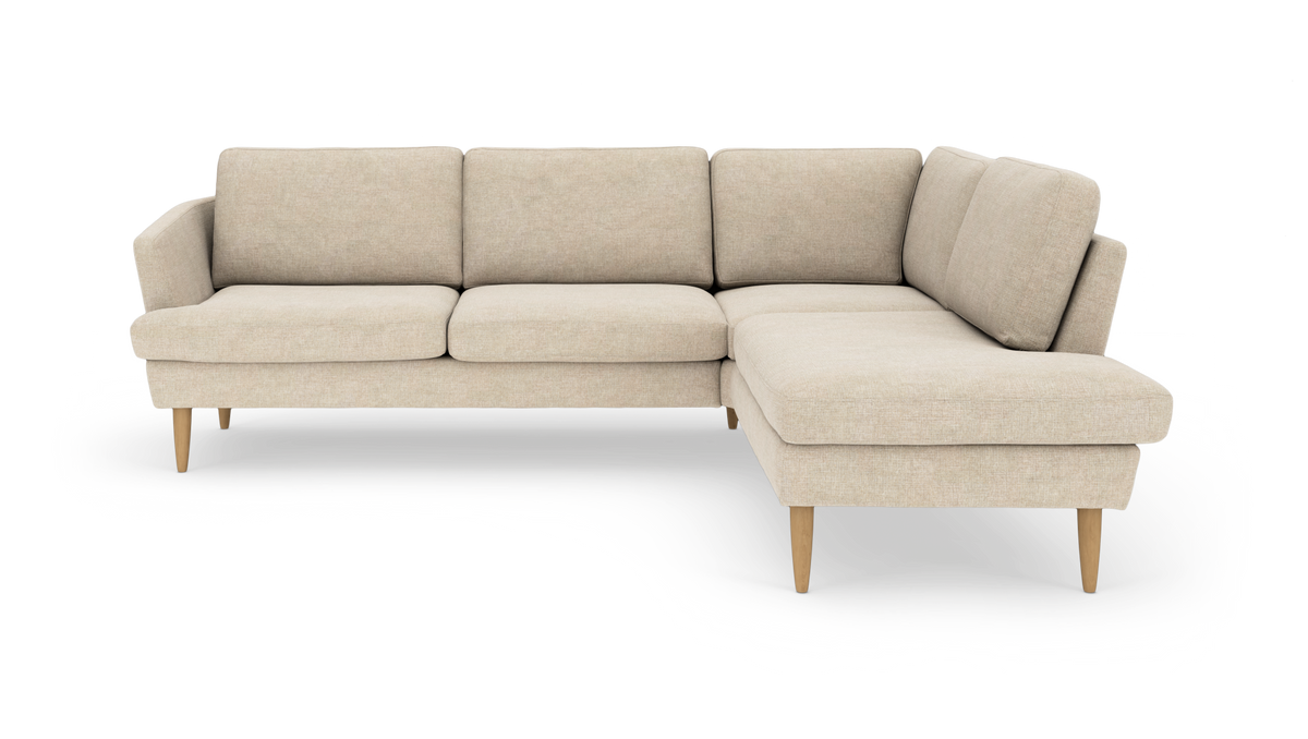 Beige hjørnesofa med chaiselong til højre og koniske ben i lyst træ, frilagt på hvid baggrund.