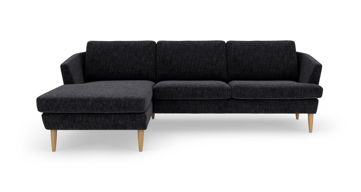 Mørkegrå hjørnesofa med venstrevendt chaiselong og lyse træben, frilagt på hvid baggrund.