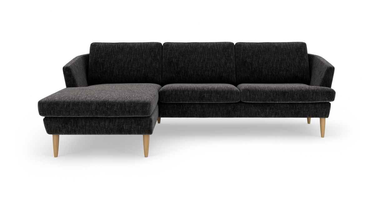 Mørkegrå hjørnesofa med venstrevendt chaiselong og lyse træben, frilagt på hvid baggrund.