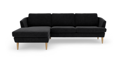 Sort hjørnesofa med venstrevendt chaiselong og lyse træben, frilagt på hvid baggrund.
