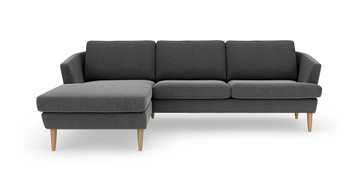Mørkegrå hjørnesofa med venstrevendt chaiselong og lyse træben, frilagt på hvid baggrund.