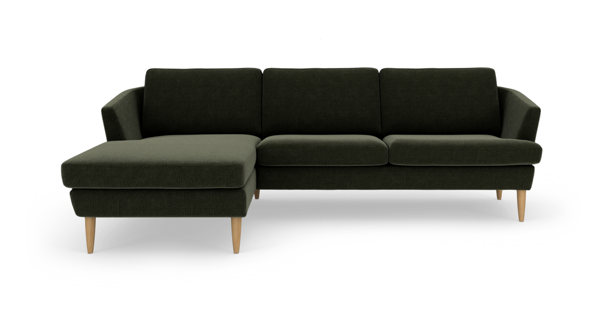 Mørkegrøn hjørnesofa med venstrevendt chaiselong og lyse træben, fritlagt mod hvid baggrund.
