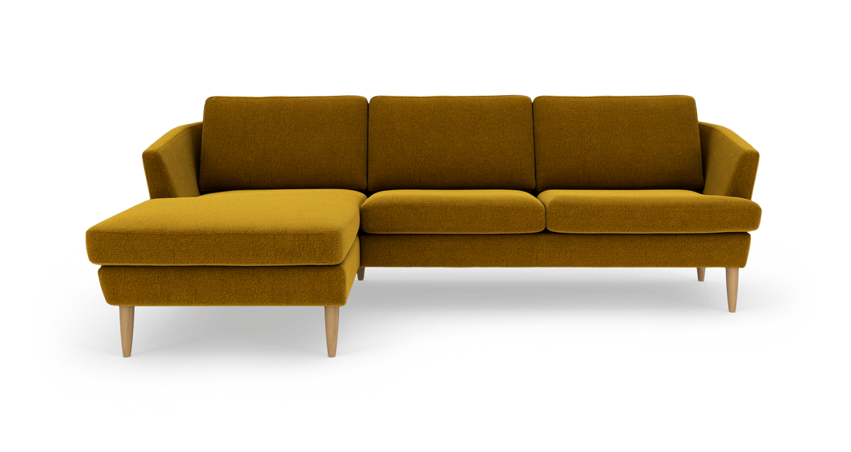 Sennepsgul hjørnesofa med chaiselong til venstre og træben, frilagt på hvid baggrund.