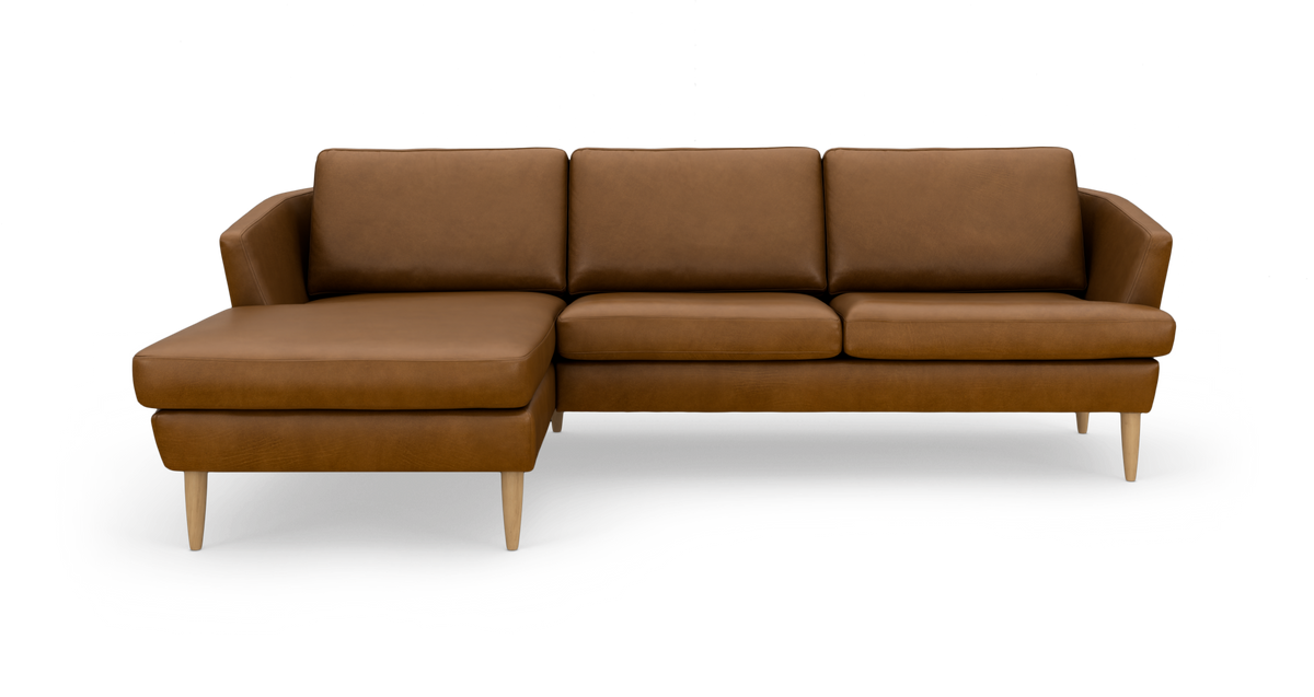 Brun hjørnesofa med chaiselong til venstre og lyse træben, fotograferet forfra på hvid baggrund.