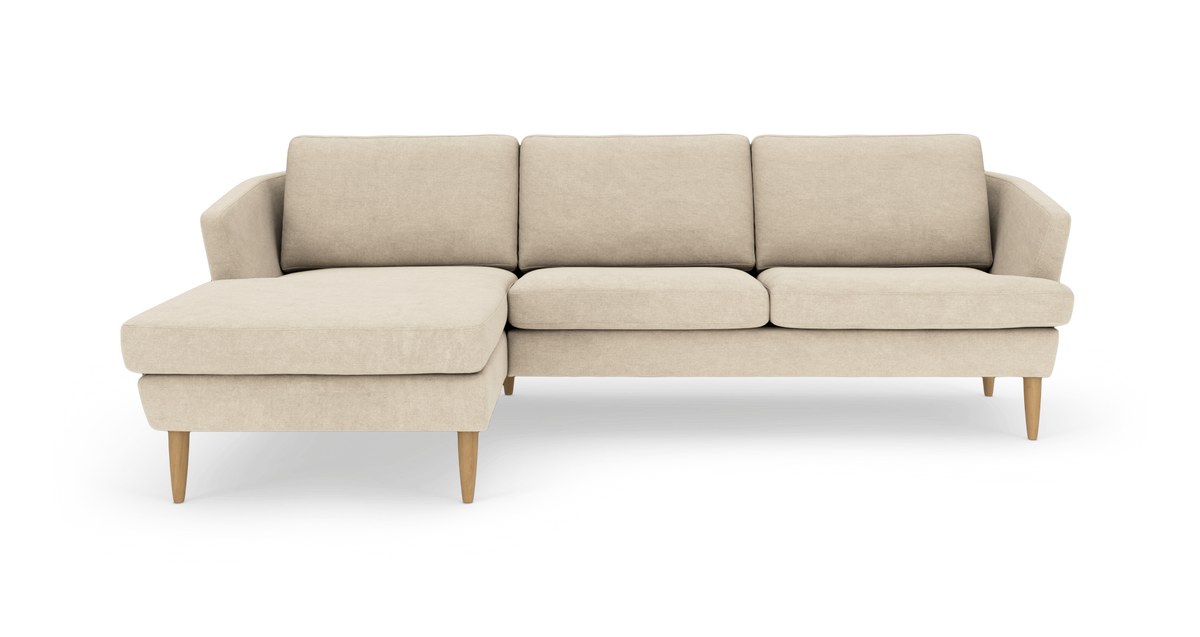 Beige hjørnesofa med venstre chaiselong og koniske træben, frilagt på hvid baggrund.