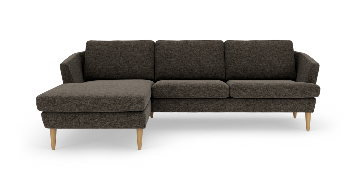 Mørkegrå hjørnesofa med venstrevendt chaiselong og koniske ben i lyst træ, frilagt på hvid baggrund.