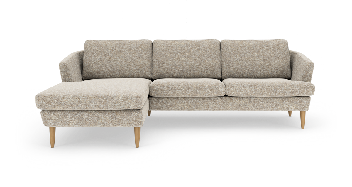 L-sofa med venstrevendt chaiselong i lysebeige stof og koniske træben, frilagt på hvid baggrund.