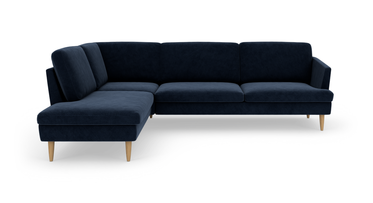 Mørkeblå L‑formet hjørnesofa med chaiselong til venstre og lyse træben, fritlagt på hvid baggrund.