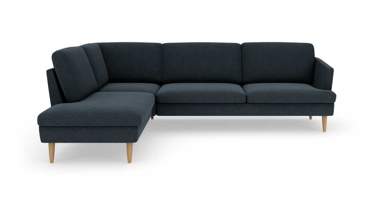 Mørkeblå hjørnesofa med venstrevendt chaiselong, stofbetræk og lyse træben på hvid baggrund.