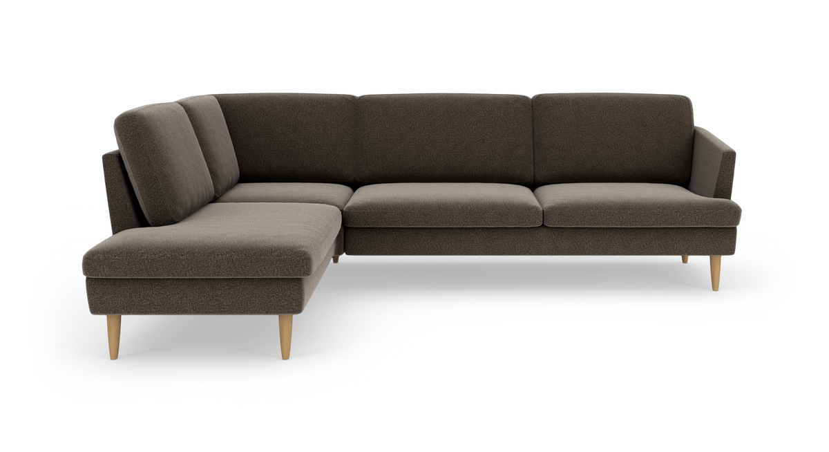Mørkegrå L‑sofa med chaiselong til venstre og koniske træben, vist på hvid baggrund.