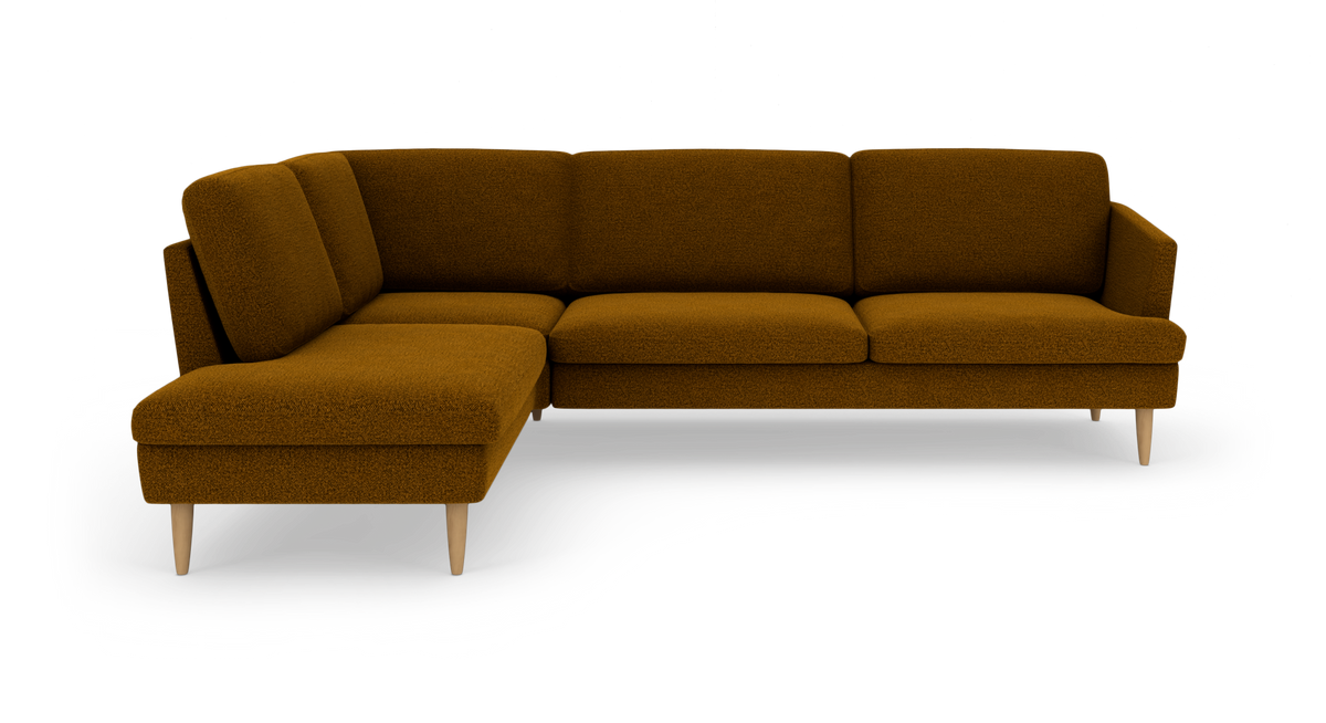 Modulær L‑sofa i mørk sennepsgul bouclé med træben, fotograferet skråt forfra på hvid baggrund.