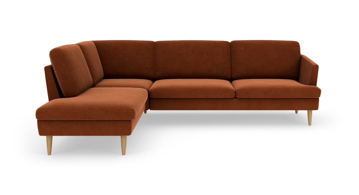 Rustrød modulopbygget hjørnesofa med chaiselong og lyse træben, frilagt på hvid baggrund.
