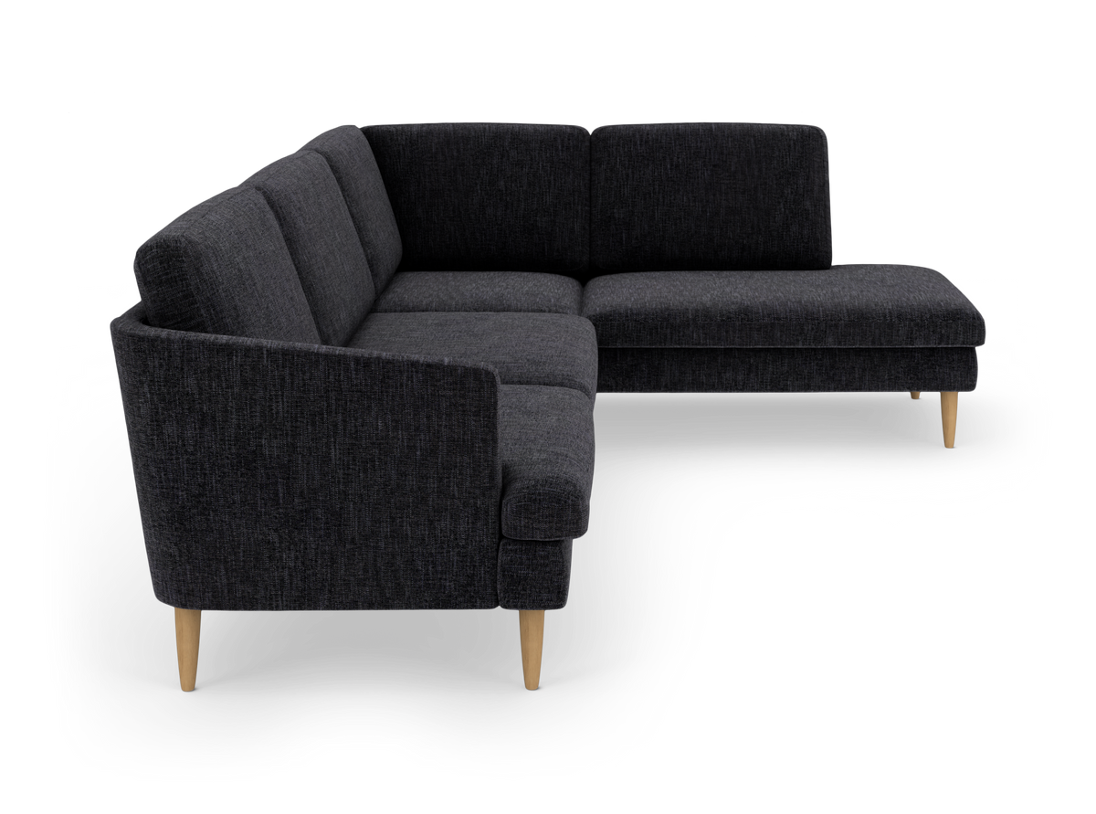 Mørkegrå L‑formet hjørnesofa med chaiselong og lyse træben, frilagt på hvid baggrund.