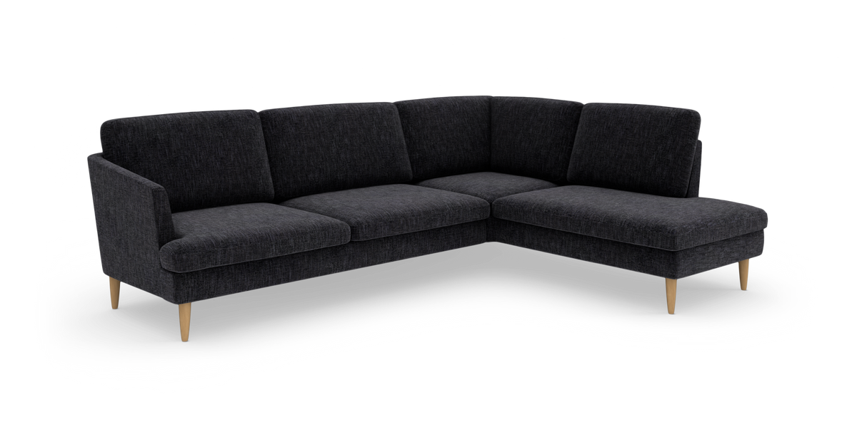 Mørkegrå L‑formet hjørnesofa med chaiselong og lyse træben på hvid baggrund.