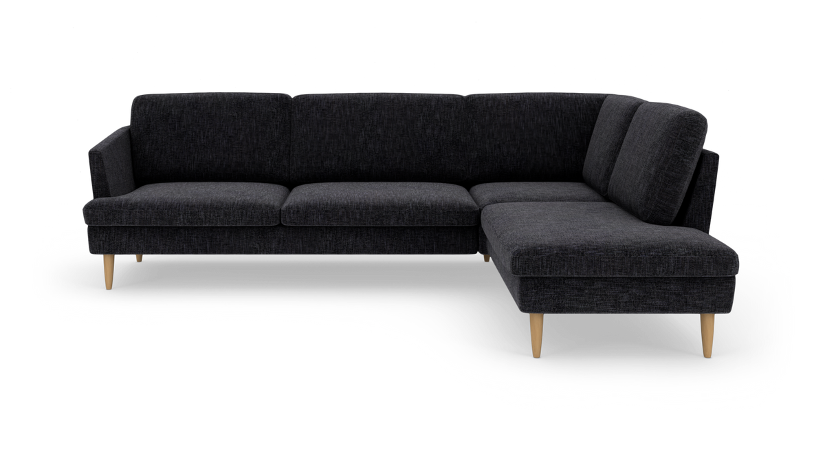 Mørkegrå L-formet sofa med chaiselong til højre og lyse træben.
