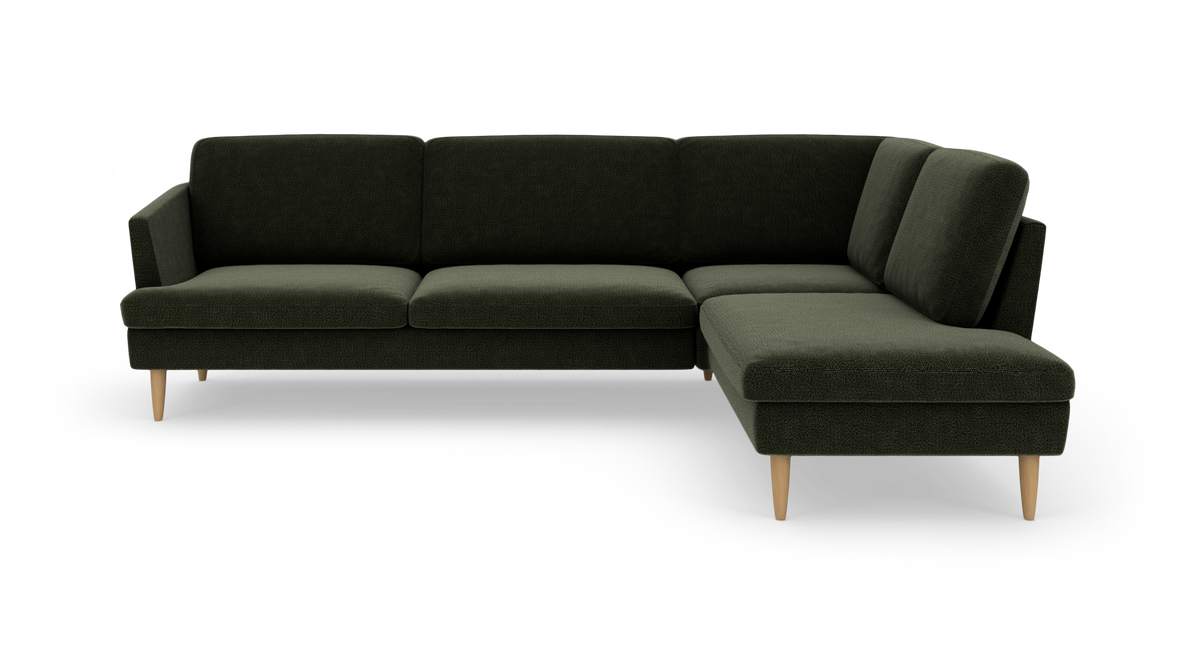 Mørkegrøn L‑sofa med chaiselong til højre og lyse træben, frilagt på hvid baggrund.