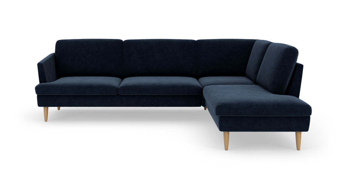 Mørkeblå hjørnesofa med chaiselong til højre og lyse træben, frilagt mod hvid baggrund.