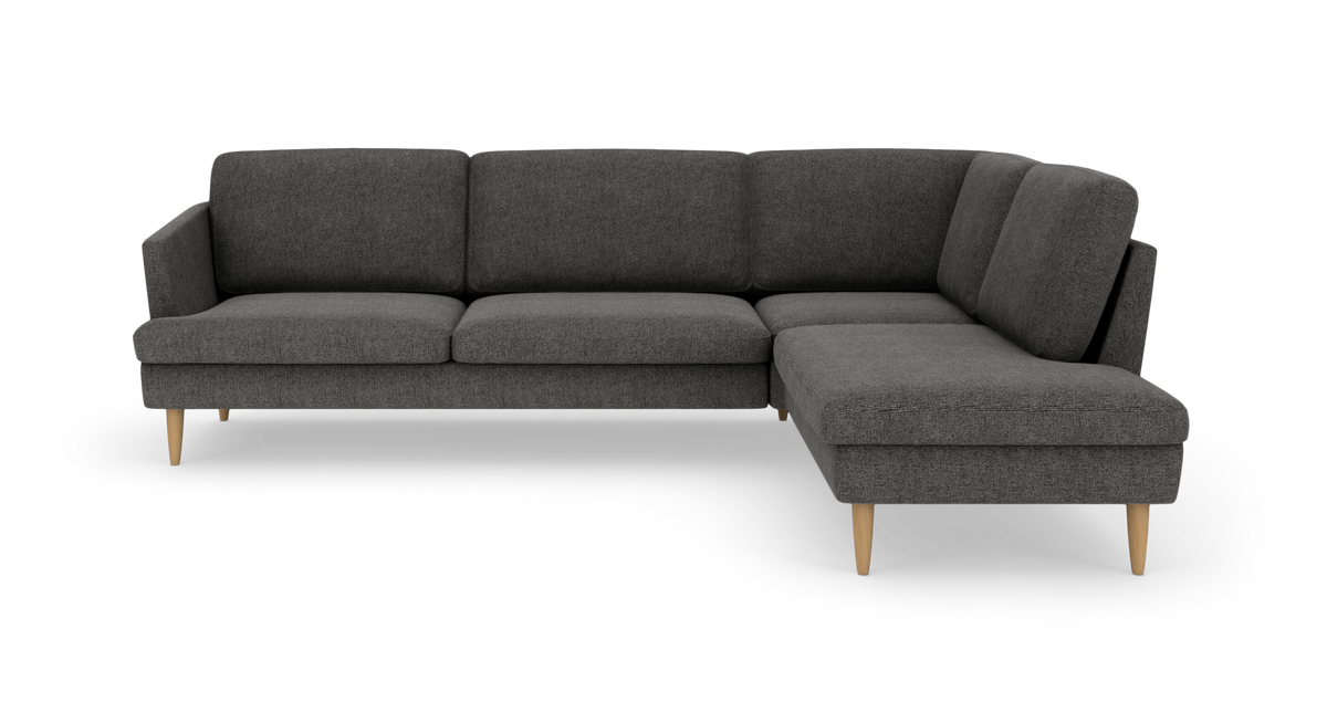 Mørkegrå hjørnesofa med chaiselong til højre og lyse træben.
