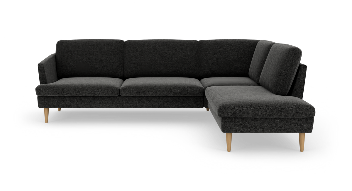Mørkegrå hjørnesofa med chaiselong til højre og lyse, tilspidsede træben.