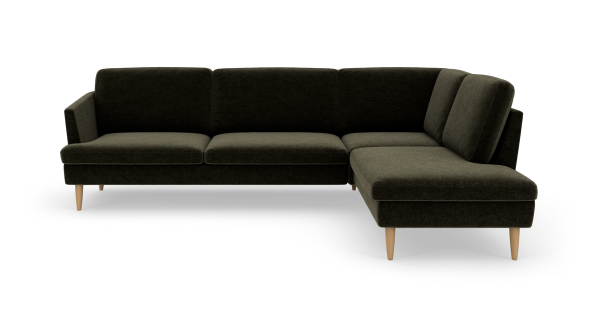 Mørkegrøn L-formet hjørnesofa med chaiselong til højre og lyse træben, frilagt på hvid baggrund.