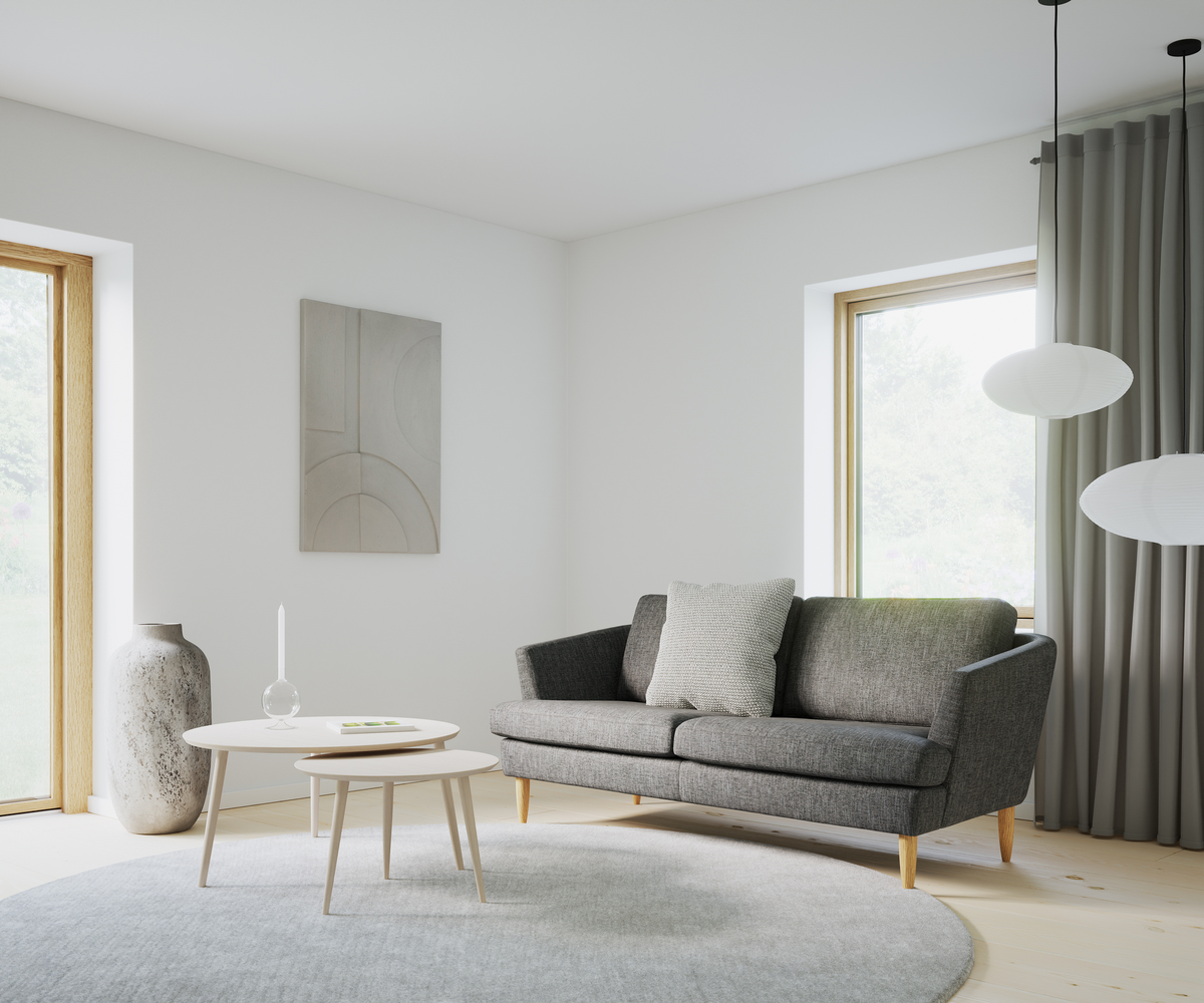 Lys stue i skandinavisk stil med grå sofa, runde sofaborde, stor vase, vægkunst, runde pendellamper, gardiner og rundt tæppe i neutrale nuancer.