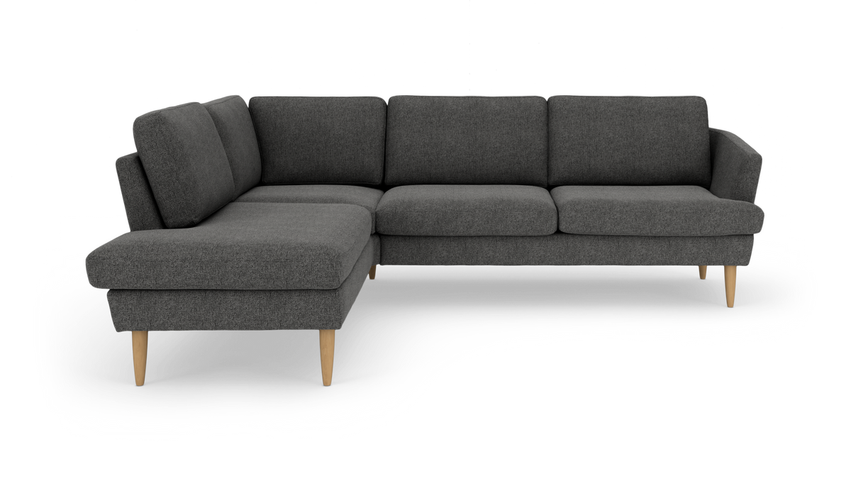 Mørkegrå L‑formet hjørnesofa med chaiselong til venstre og lyse træben, frilagt på hvid baggrund.