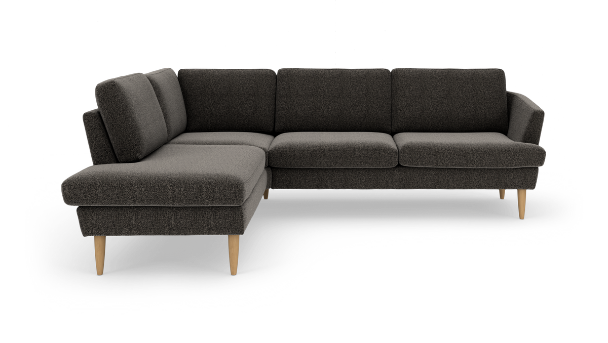 Mørkegrå L‑formet hjørnesofa med venstrevendt chaiselong og koniske træben, frilagt på hvid baggrund.