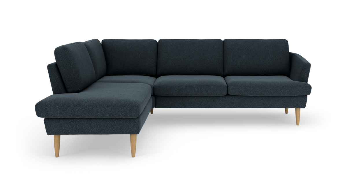 Mørkeblå L‑formet hjørnesofa med træben, fritlagt på hvid baggrund.