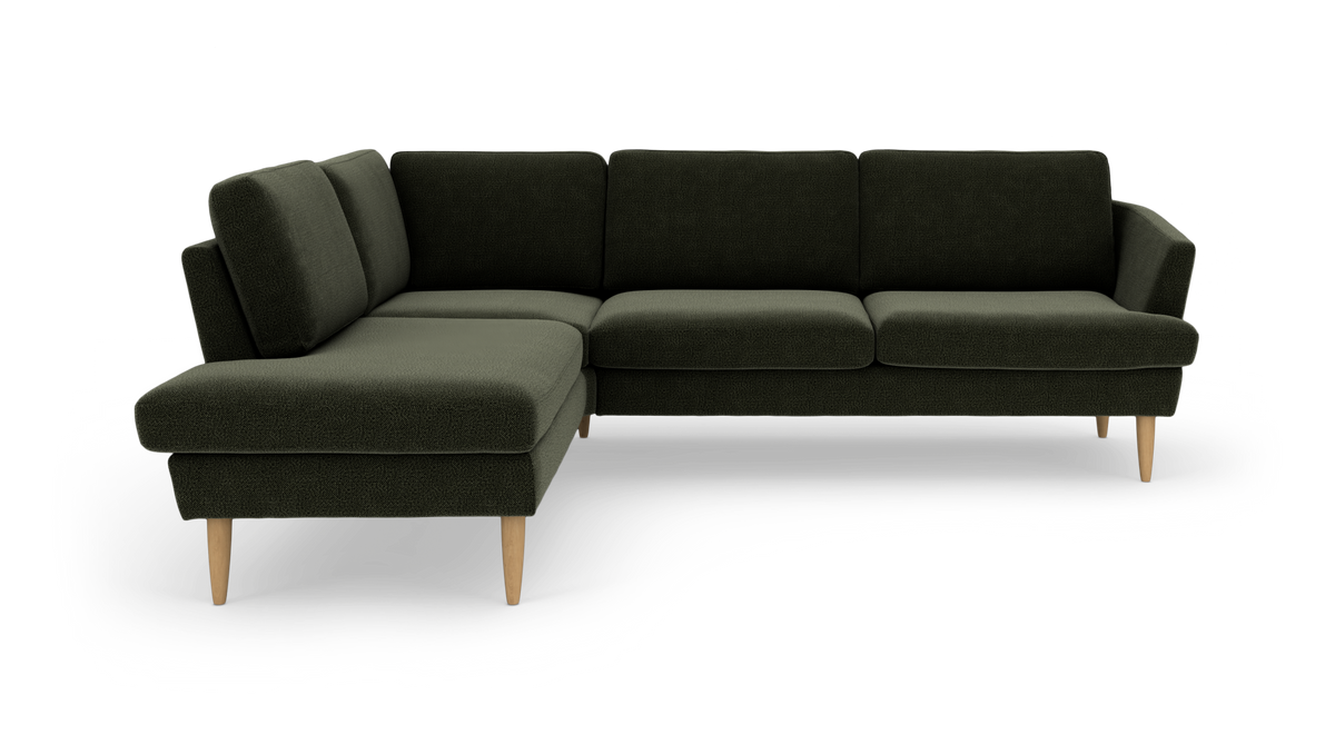 Mørkegrøn hjørnesofa med venstre chaiselong og lyse træben, frilagt på hvid baggrund.