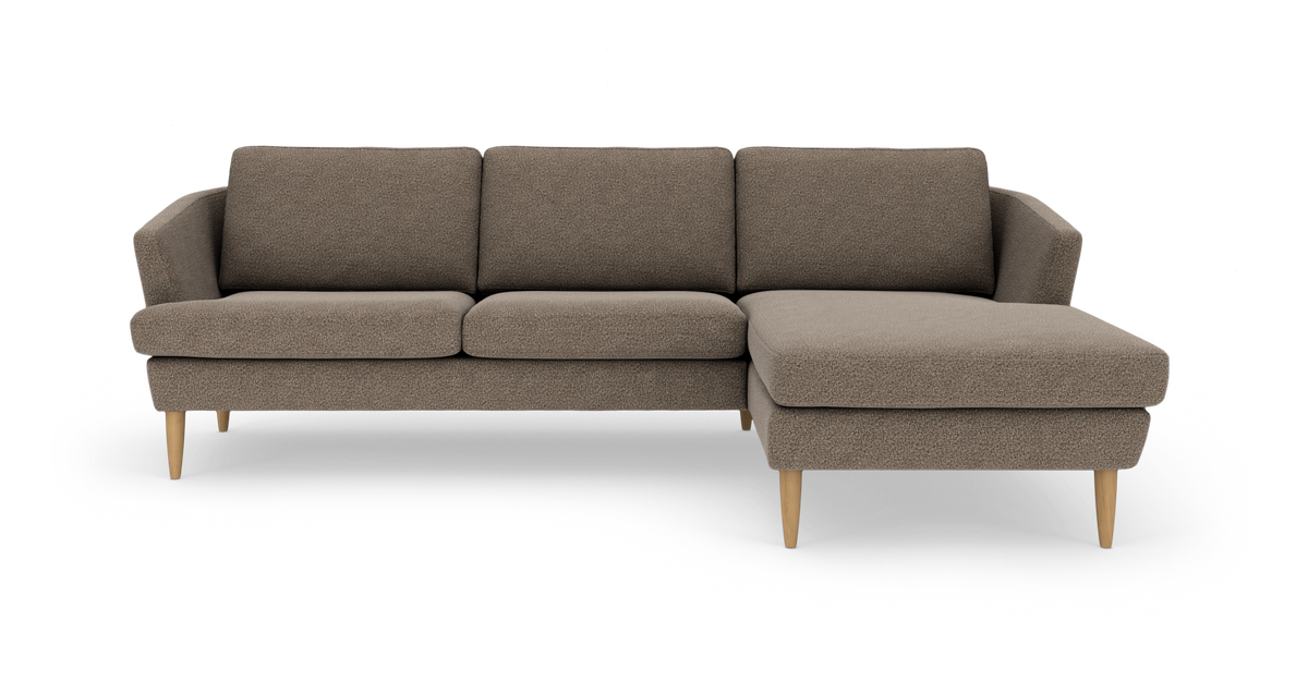 Hjørnesofa med chaiselong til højre i beige/brunt stof med lyse træben, frilagt på hvid baggrund.