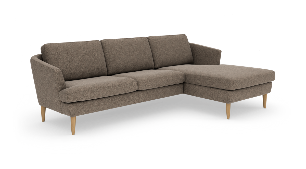 L-formet sofa i beige/taupe stof med chaiselong til højre og koniske ben i lyst træ.