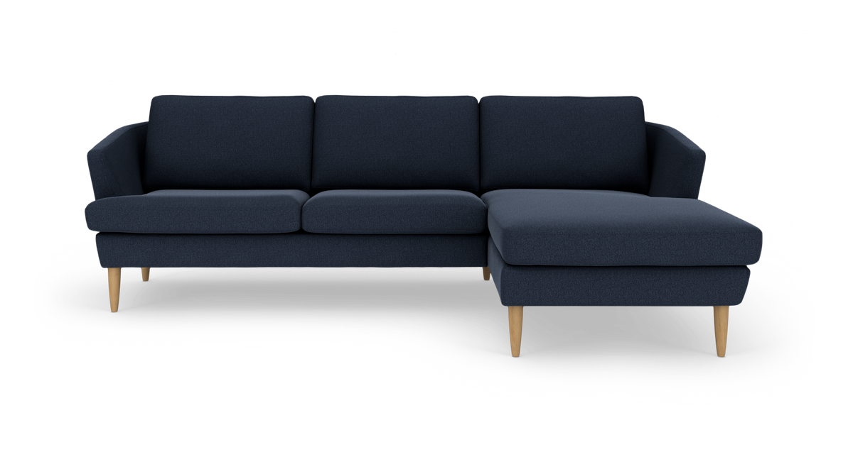 Mørkeblå hjørnesofa med chaiselong til højre og lyse træben.
