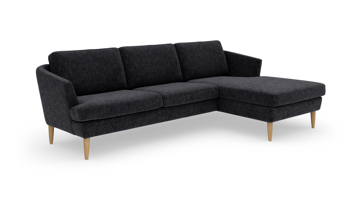 Mørkegrå hjørnesofa med chaiselong til højre og slanke træben.