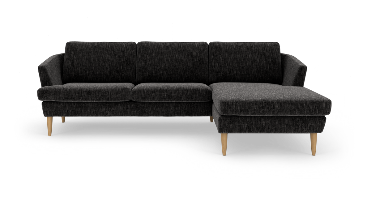 Mørkegrå hjørnesofa med højrevendt chaiselong og lyse træben, frilagt på hvid baggrund.