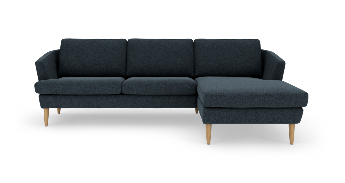 Mørkeblå hjørnesofa med chaiselong til højre og lyse træben.