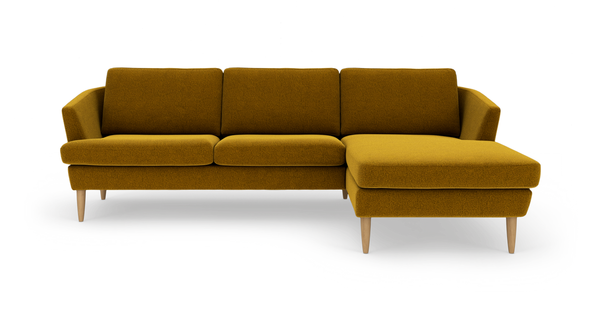 Sennepsgul hjørnesofa med chaiselong til højre og træben, frilagt på hvid baggrund.