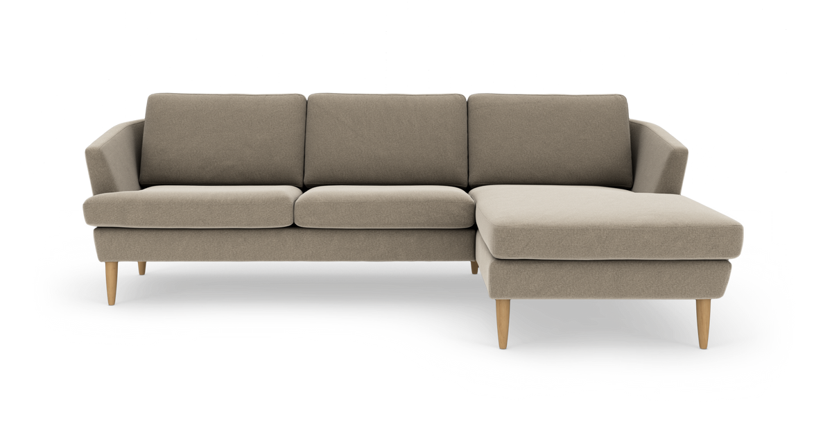 Beige L‑formet 3‑personers sofa med højre chaiselong og lyse træben, frilagt på hvid baggrund.