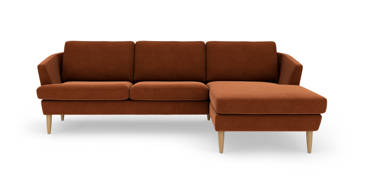 Rustfarvet hjørnesofa med chaiselong til højre og træben, frilagt på hvid baggrund.
