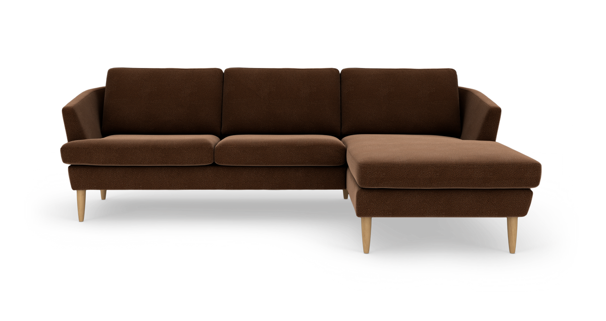 Brun hjørnesofa med chaiselong til højre og lyse træben, set forfra.