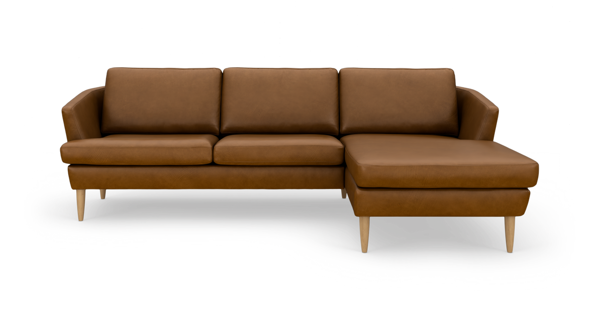 Brun lædersofa med chaiselong i højre side og lyse træben, fritlagt mod hvid baggrund.