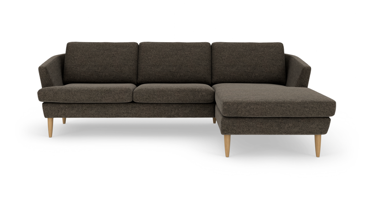 Mørkegrå hjørnesofa med chaiselong til højre og lyse træben.