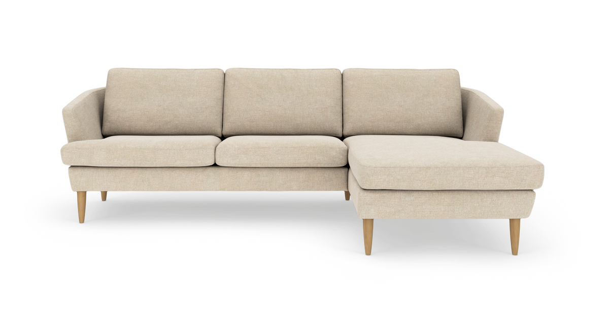 Beige hjørnesofa med chaiselong til højre, træben og tre sædehynder, produktbillede forfra.