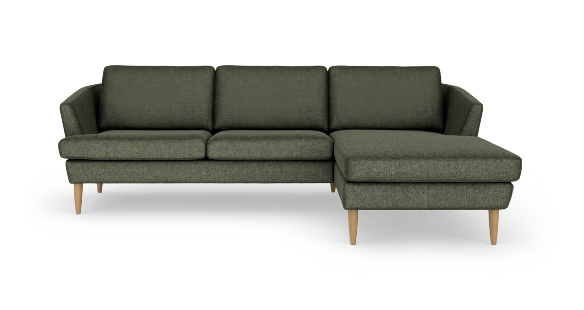 Mørkegrøn modulsofa med chaiselong til højre på træben, frilagt mod hvid baggrund.
