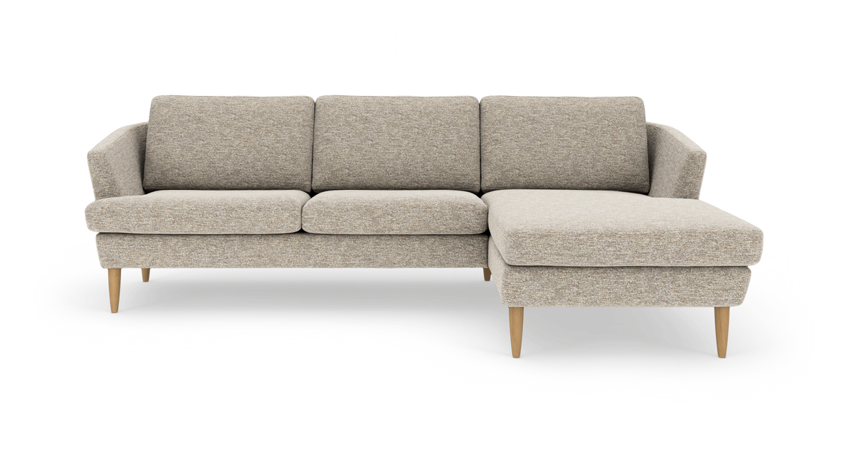 Beige 3-personers sofa med chaiselong til højre og lyse træben, frilagt på hvid baggrund.