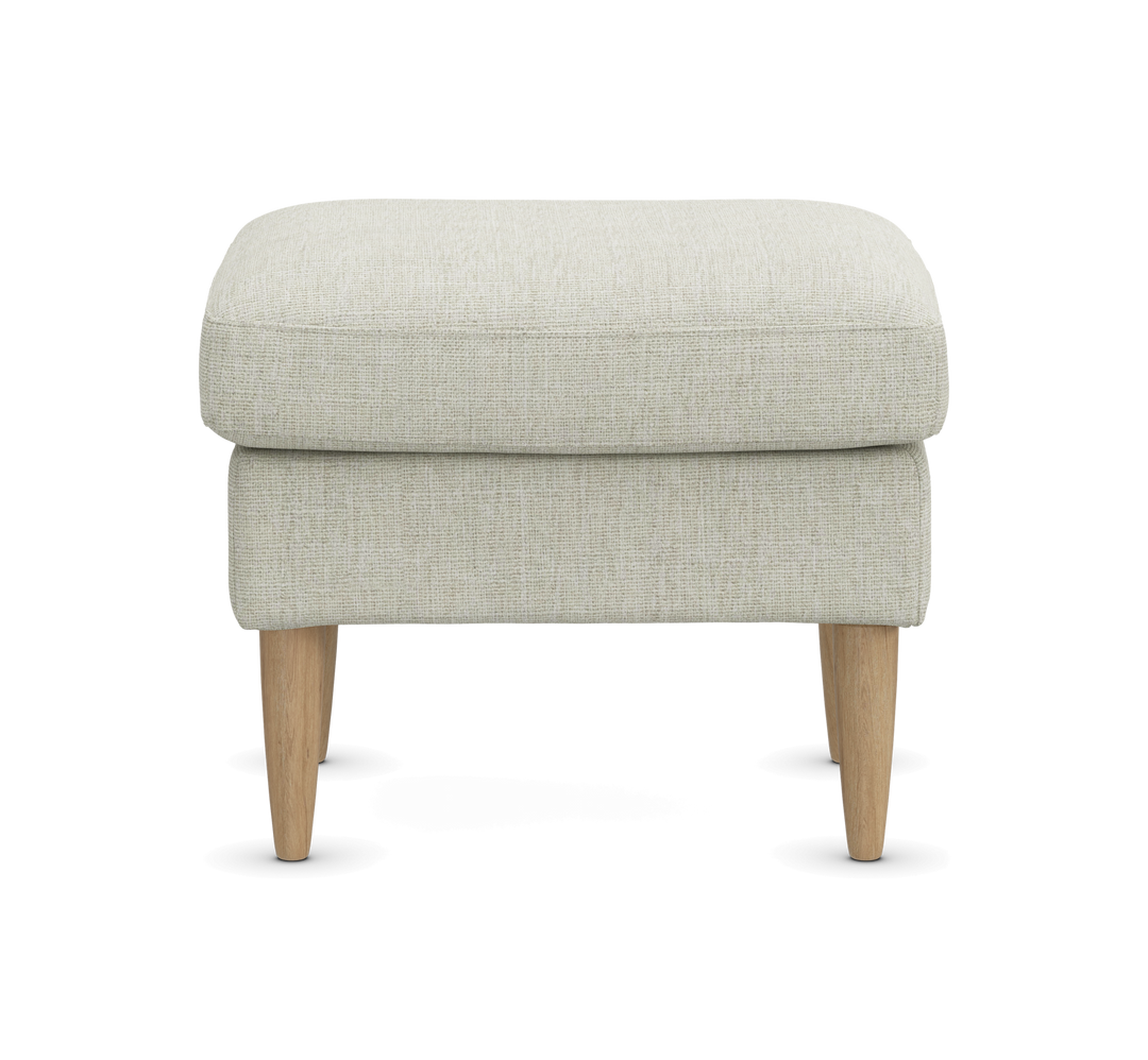Lys beige puf/ottoman med tekstilbetræk og lyse træben, fotograferet forfra på neutral baggrund.