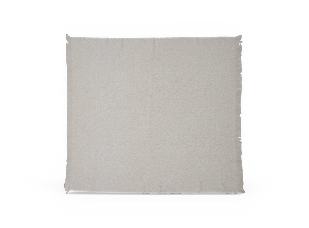 Lysebeige plaid med fine frynser langs kanterne, lagt fladt på hvid baggrund.