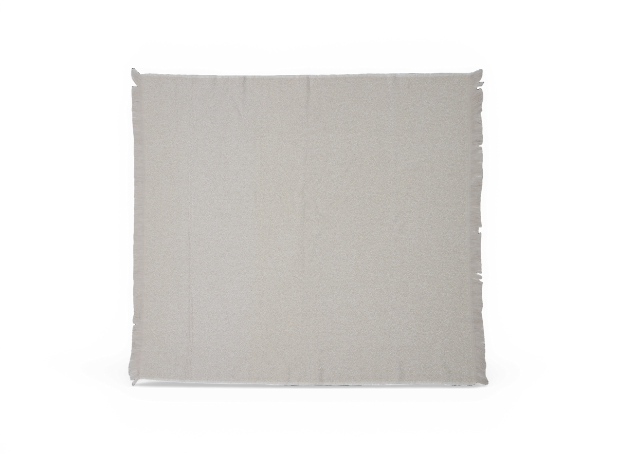 Lysebeige plaid med fine frynser langs kanterne, lagt fladt på hvid baggrund.