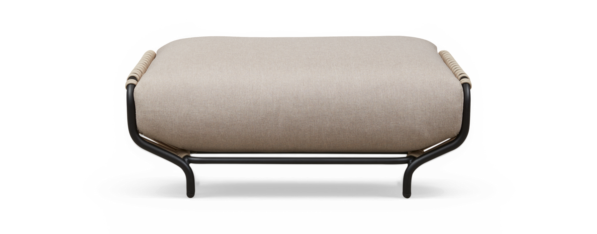 Beige polstret ottoman med sort rørformet metalramme og rebdetaljer på enderne, fritlagt mod sort baggrund, set lige forfra.