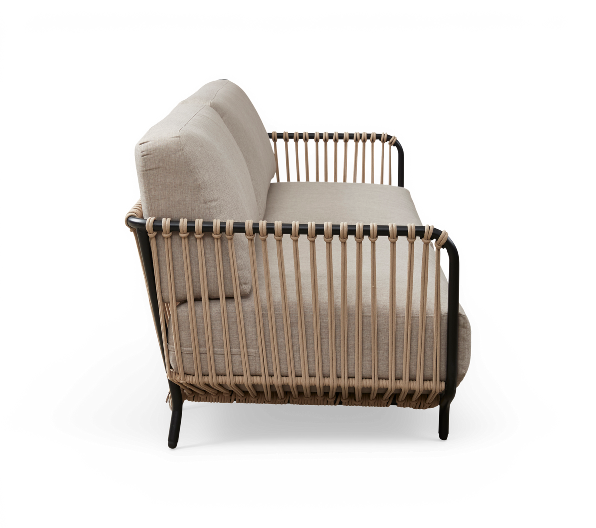 Sofa i sidevinkel med beige puder og flettet reb-/rattanramme på sort metalstel, frilagt.