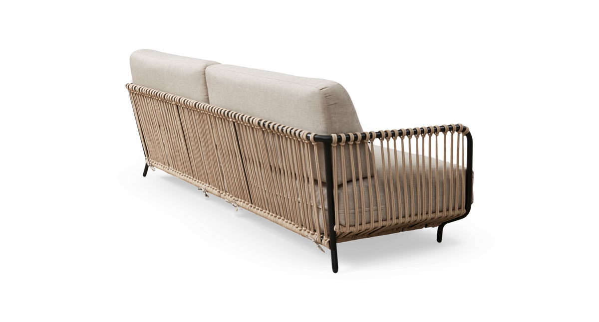 Sofa med lysebeige puder og flettet reb/rottingramme samt sorte metalben, set bagfra i studiemiljø.